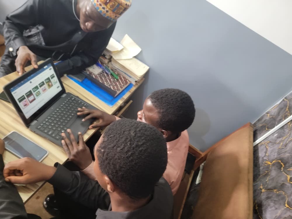 Fawaz guiding two members through online freelance jobs on a laptop