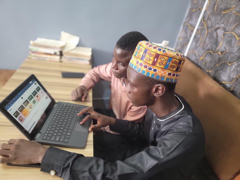 Two young men learning freelancing on a laptop, looking at online jobs